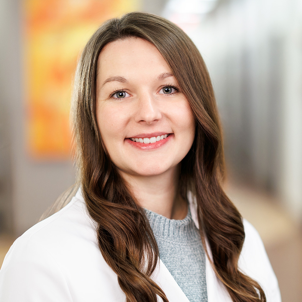 Nurse practitioner Sarah Cantrell is standing in the clinic hallway and is smiling.