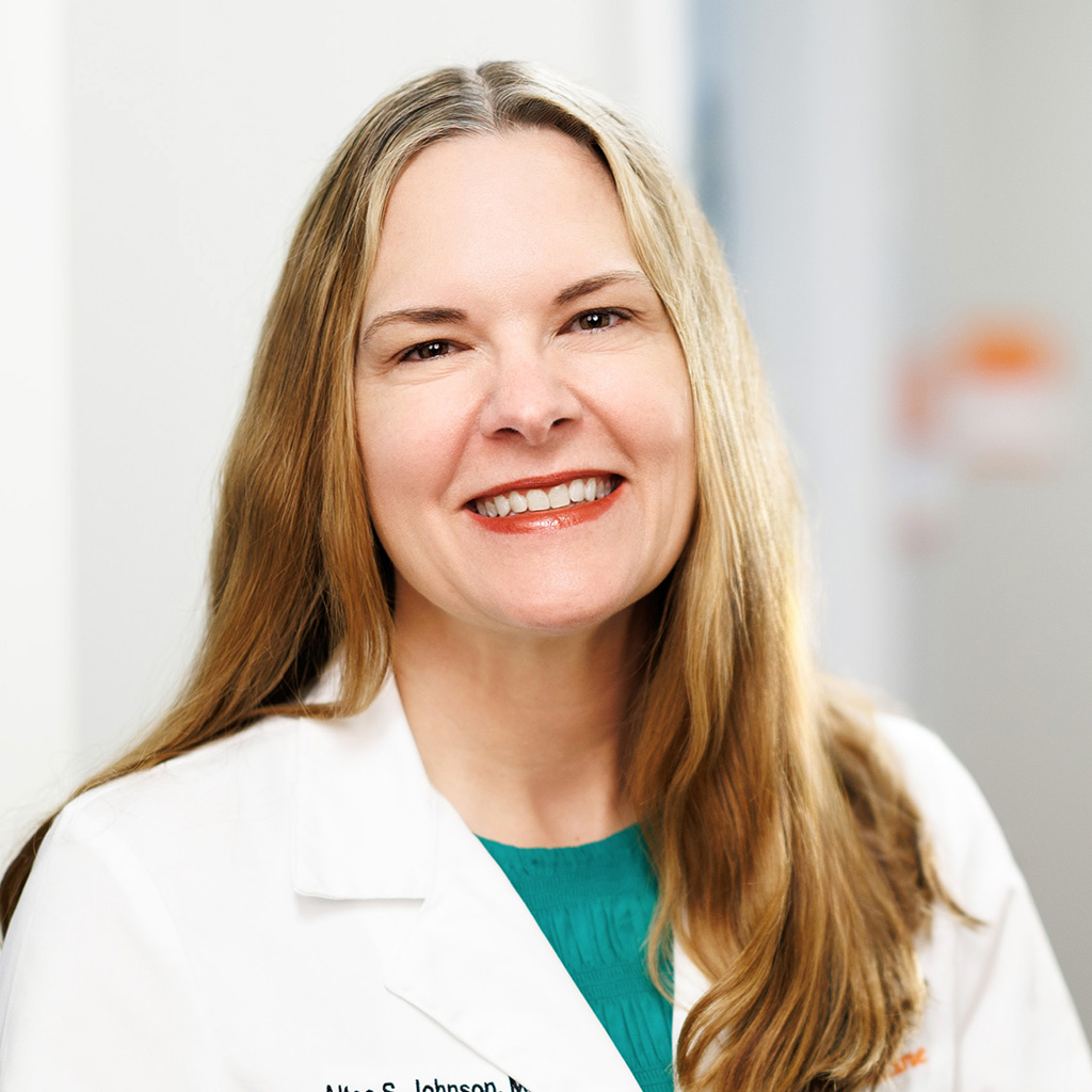 Dr. Johnson smiling and wearing her white coat in the clinic hallway.