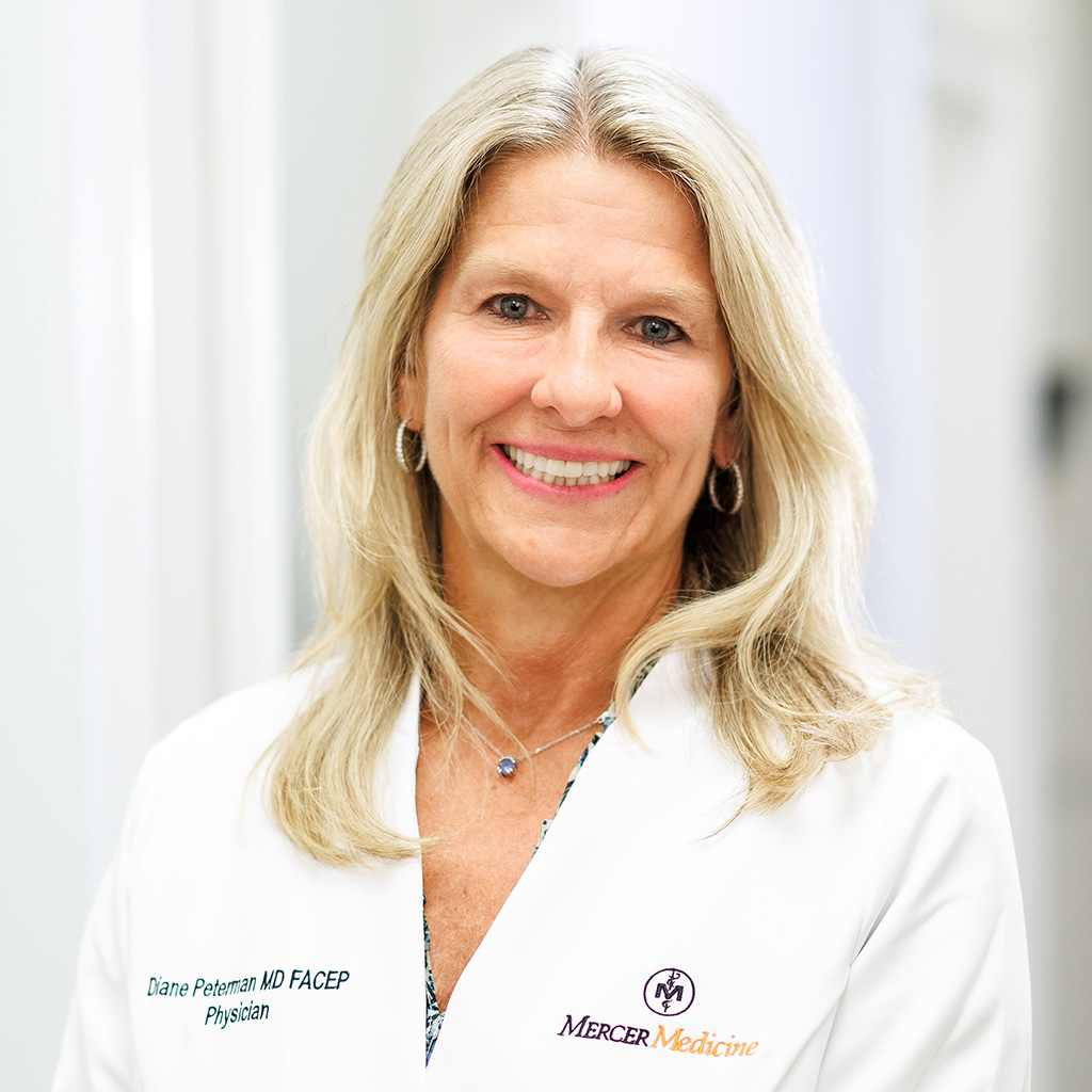 Dr. Peterman smiling and wearing her white coat in the clinic hallway.