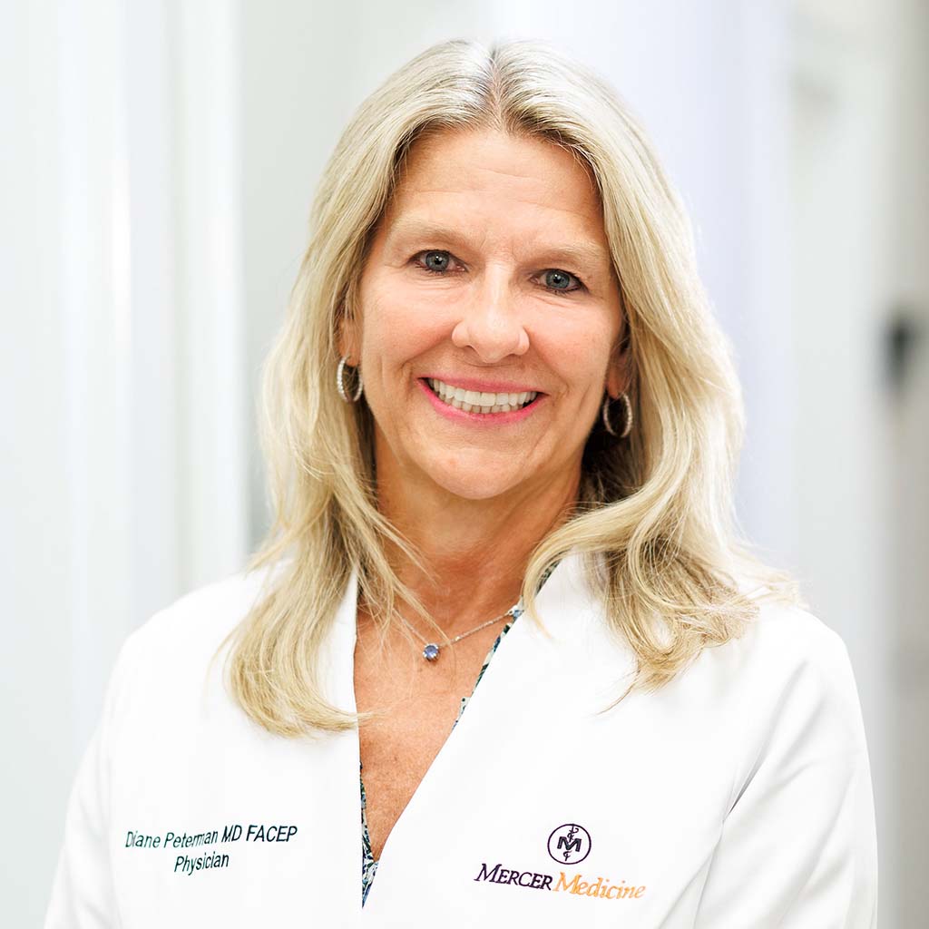 Dr. Peterman smiling and wearing her white coat in the clinic hallway.